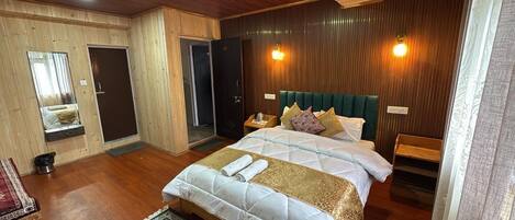 A bedroom with a large bed, wooden walls, a mirror, and a green rug.