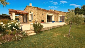 Una casa in pietra con tetto in tegole, un portico coperto e un prato curato.
