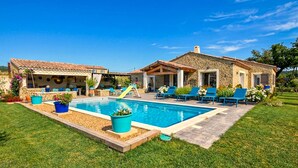 Una piscina con sedie a sdraio, uno scivolo e un edificio in pietra con tetto in tegole.