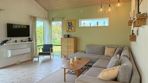 Un soggiorno con divano, tavolino, televisore, mobile e finestra con tende.