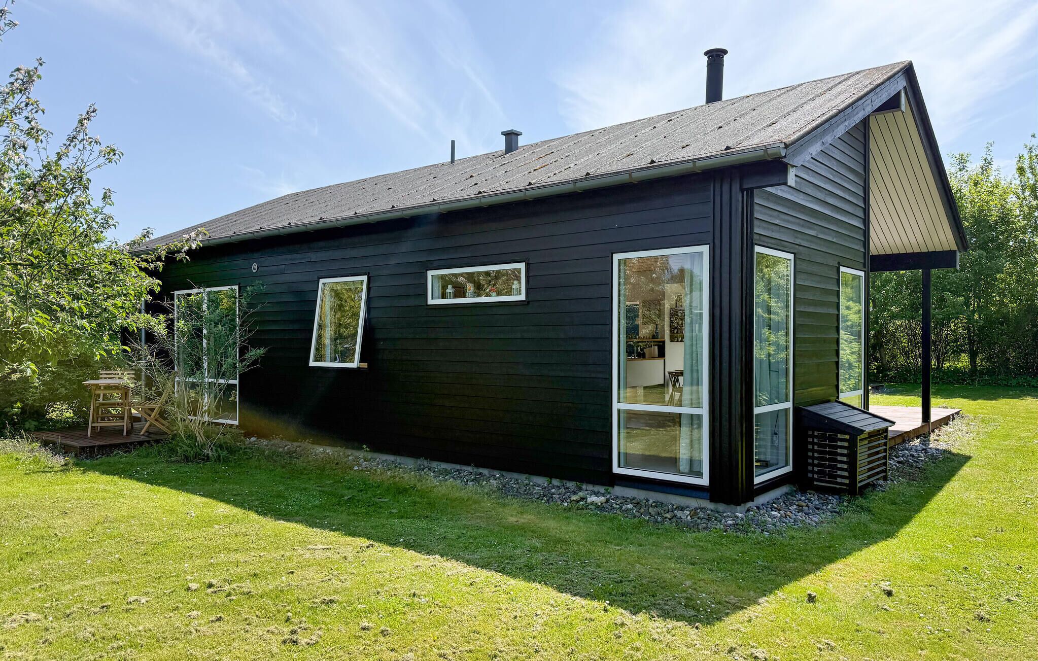 Een modern zwart huis met grote ramen en een overdekte veranda.