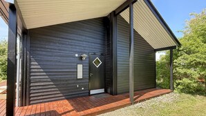 Un edificio moderno con facciata scura, un rivestimento in legno e una porta nera con una targa con il numero.