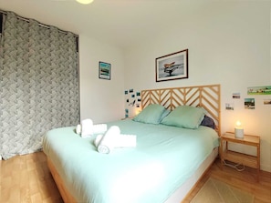 Ein Schlafzimmer mit Bett, Kissen, einem Nachttisch und einer Wand mit Bildern.