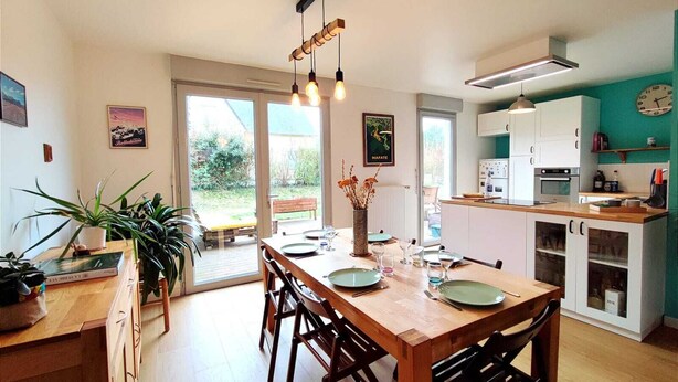Una cocina moderna con una mesa de comedor, sillas y una lámpara colgante.