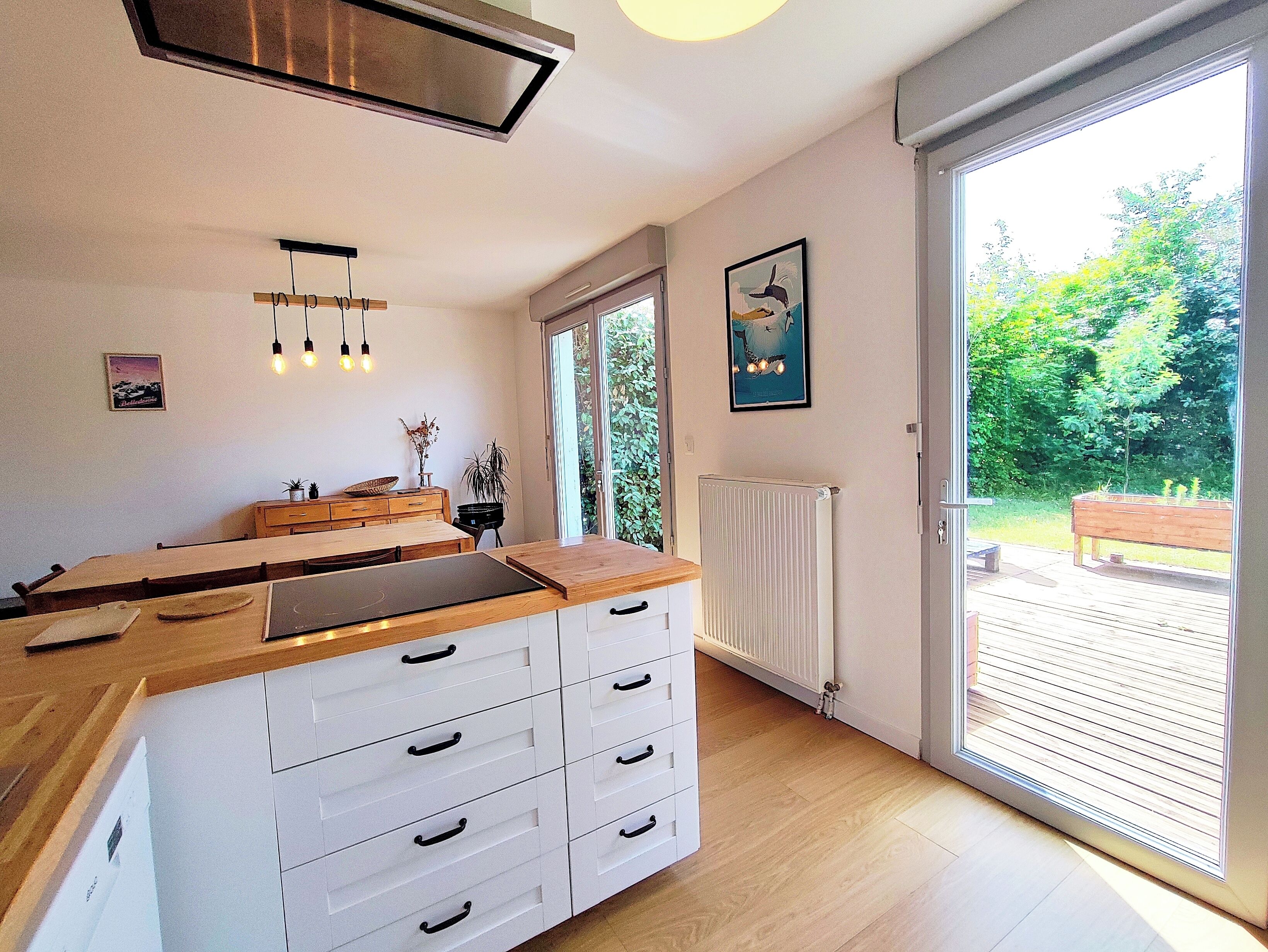 Una cocina moderna con encimera de madera, armarios blancos y un amplio ventanal.