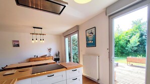 Una cocina moderna con encimera de madera, armarios blancos y un amplio ventanal.