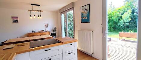 Una cocina moderna con encimera de madera, armarios blancos y un amplio ventanal.