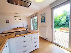 Eine moderne Küche mit einer Holzarbeitsplatte, weißen Schränken und einem großen Fenster.