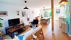 Una sala de estar moderna con televisor, sofá y comedor.