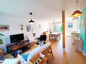 Ein modernes Wohnzimmer mit Fernseher, Sofa und Essbereich.