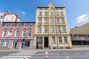 Ein mehrstöckiges Gebäude mit einem Salon im Erdgeschoss, einer sichtbaren Schaufensterfront mit Beschilderung und blauem Himmel.
