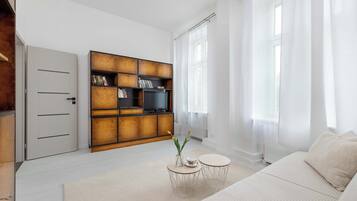Un salon moderne comprenant un canapé, une table basse, une bibliothèque et un téléviseur.