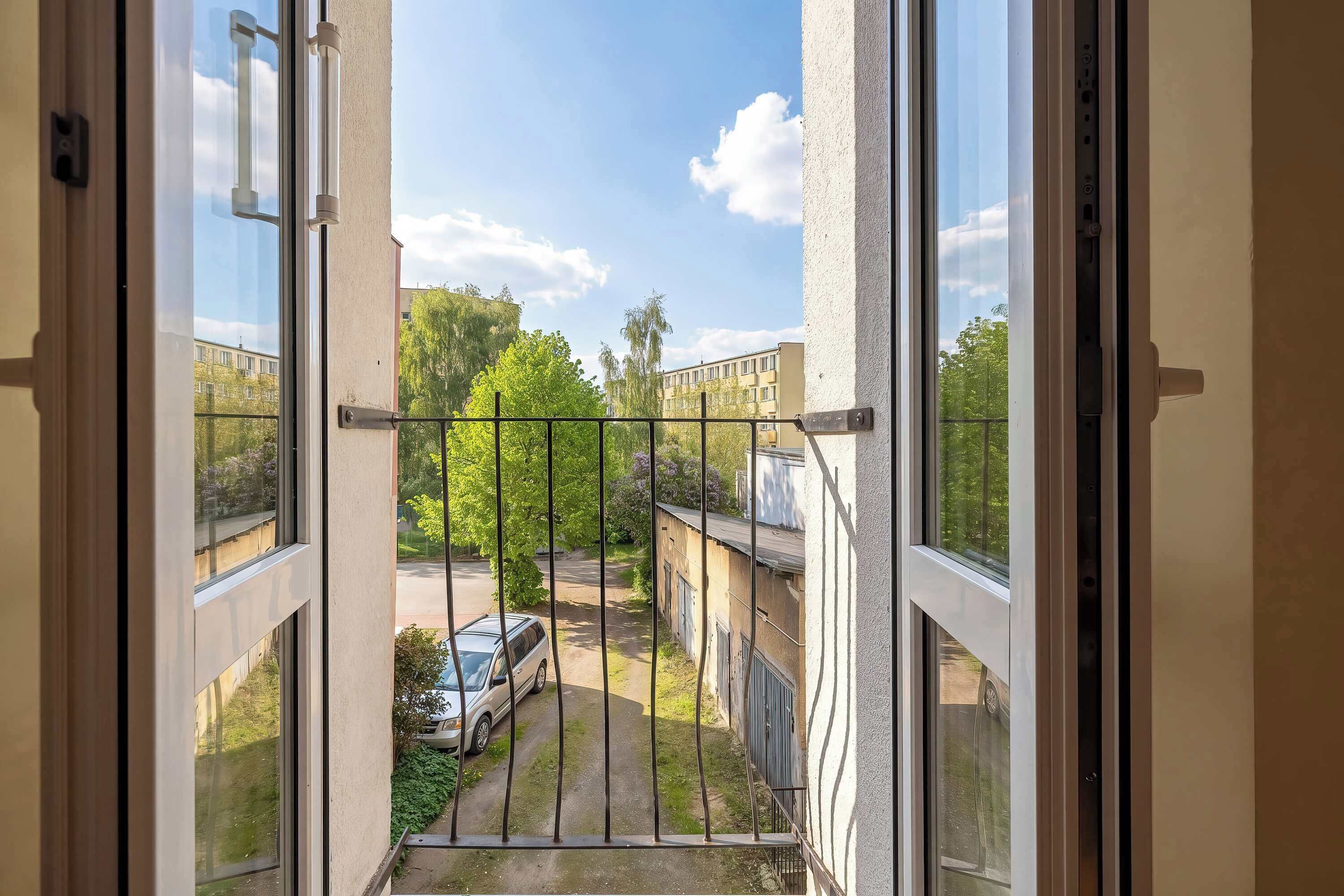 A balcony with a view of a parking area and buildings.