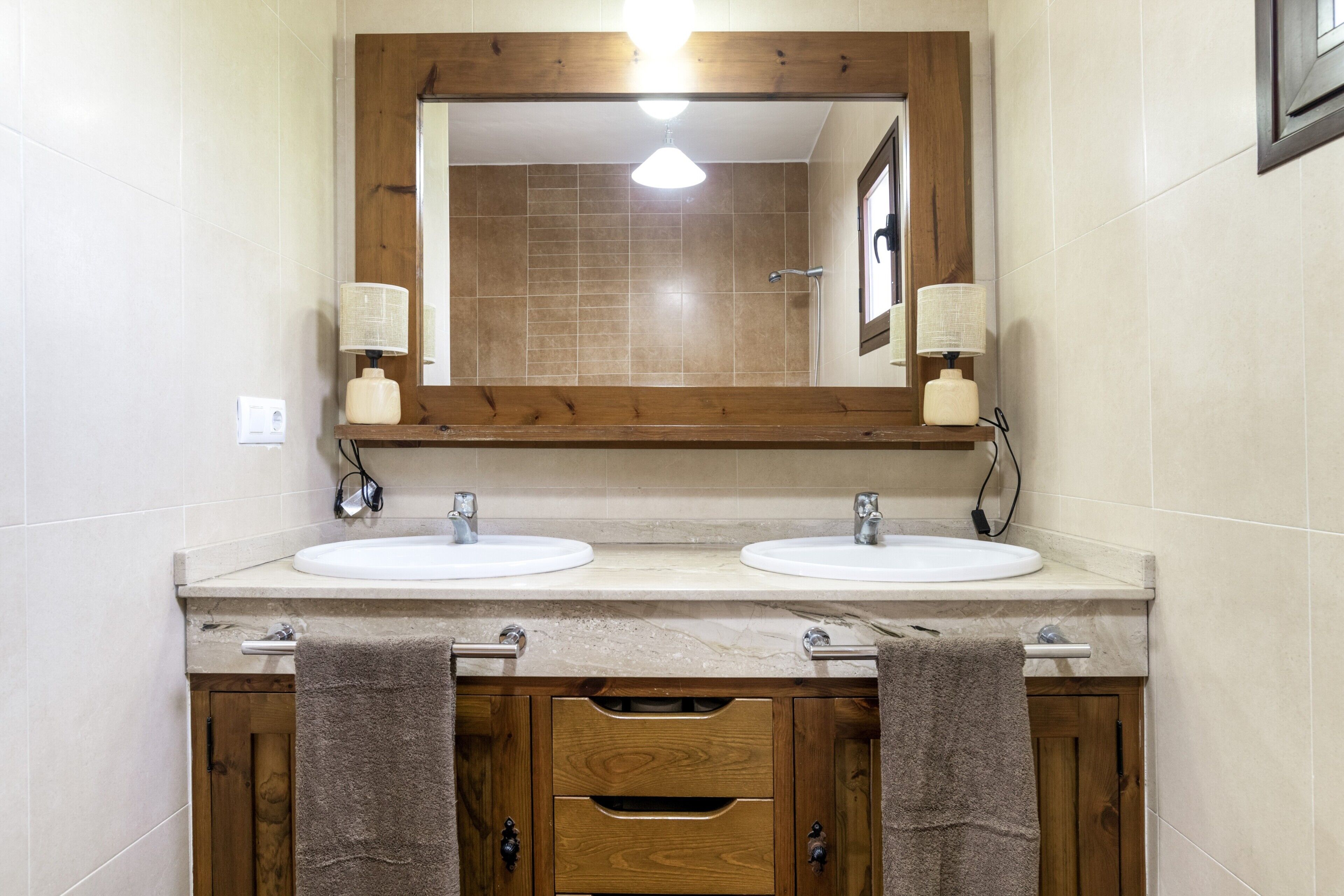 A bathroom with two sinks, a mirror, and wooden cabinets with towels.