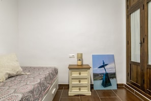 Ein Schlafzimmer mit einem Bett, einem Nachttisch mit Lampe, einer Kommode und einem Bild an der Wand.
