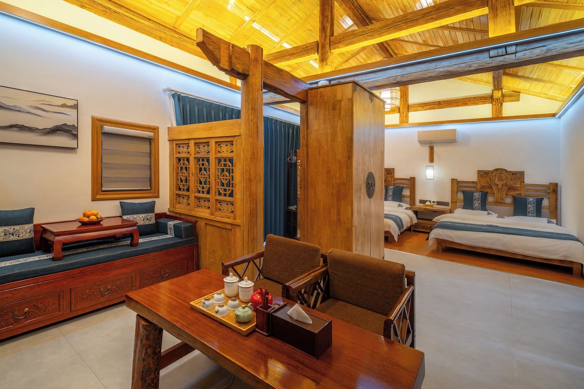 A traditional-style room with a wooden ceiling, a sofa, a table with teapots, and a bed.