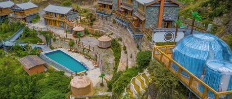 Un resort de estilo tradicional con varias habitaciones, una piscina y jardines en terrazas.