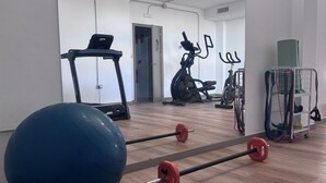 Une salle de sport équipée de matériel d’exercice, notamment un tapis de course, un vélo d’appartement et des poids libres.