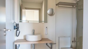Une salle de bain moderne avec un lavabo, un miroir, des toilettes et une douche.
