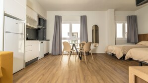 Une chambre moderne comprenant une cuisine, un coin repas et deux lits.