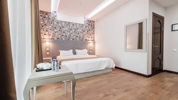 A hotel room with a bed, bedside table, and a wall with a floral pattern.