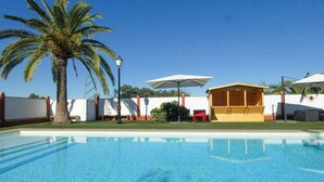 A swimming pool with a palm tree, a covered seating area, and a white fence. - Private retreat with pool near Seville (Utrera)