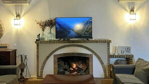 A living room with a fireplace, a television mounted above it, and two wall-mounted air conditioners. - Private retreat with pool near Seville (Utrera)