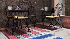 A dining area with a patterned wall, a table with chairs, and a decorative rug. - Riad in the center of the medina of Fes (Fès)