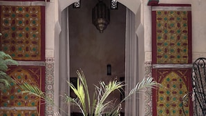 A green pot with plants on a tiled floor, a blue and white striped rug, and a chair. - Riad in the center of the medina of Fes (Fès)
