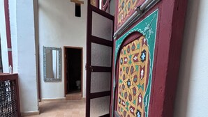 A corridor with a tiled floor, a door with intricate patterns, and a mirror on the wall. - Riad in the center of the medina of Fes (Fès)