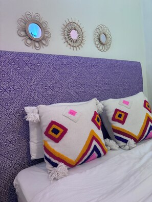 Un lit avec des coussins à motifs et une tête de lit texturée.
