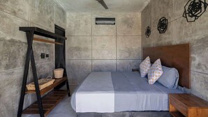 Ein Schlafzimmer mit Etagenbett, einem Holznachttisch, einem Deckenventilator und einem wandmontierten Lüftungsgitter.