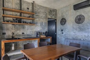 Eine moderne Küche mit Holztisch und -stühlen, eingebauten Regalen und einer Wand aus grauem Stein.