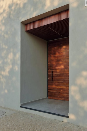 A modern building entrance with a wooden door and a slatted roof overhang. - Unique Apartment w/ Pool Access in MU Kuadru (Oaxaca de Juárez)