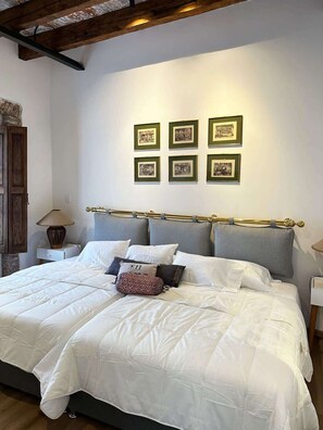 Ein Schlafzimmer mit einem großen Bett, einem hölzernen Kopfteil, einem Nachttisch mit Lampe und gerahmten Bildern an der Wand.