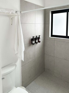 Un baño moderno con ducha, inodoro y ventana.