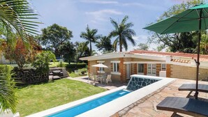 Une propriété résidentielle dotée d’une piscine, de mobilier de jardin et d’un mur en pierre.