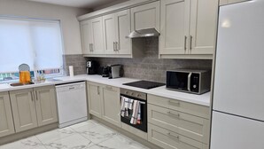 A modern kitchen with a dishwasher, stove, microwave, and a coffee maker.