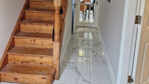 A wooden staircase leading to a room with a tiled floor and a door with a window.