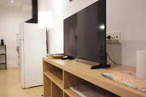 A modern room with a flat-screen TV on a wooden stand, a white refrigerator, and a lamp. - Flowers Houses 5 New, quiet, modern. (Granada)