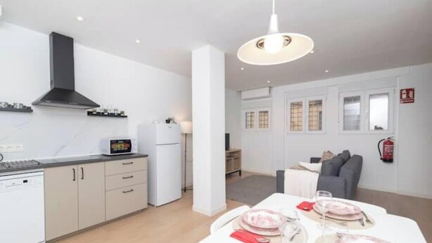 A modern kitchen with white cabinets, a black range hood, and a dining area with a table set for four.