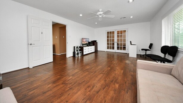 A spacious living room with hardwood flooring, a ceiling fan, recessed lighting, a television, and a sliding glass door. - Lofty Grace Home 2 - Spacious 4BR Home (Richmond)