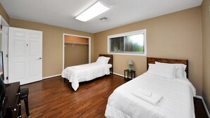A room with two beds, a closet, a window with blinds, and a desk with a chair. - Lofty Grace Home 2 - Spacious 4BR Home (Richmond)