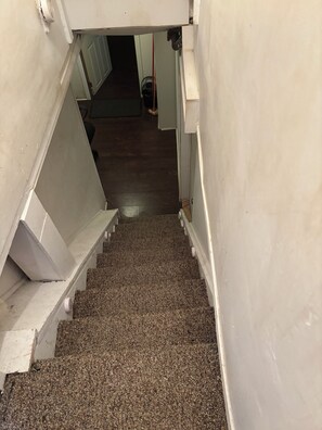 Eine Treppe mit einem strukturierten Teppich führt zu einem Raum mit weißen Wänden und einer Tür.