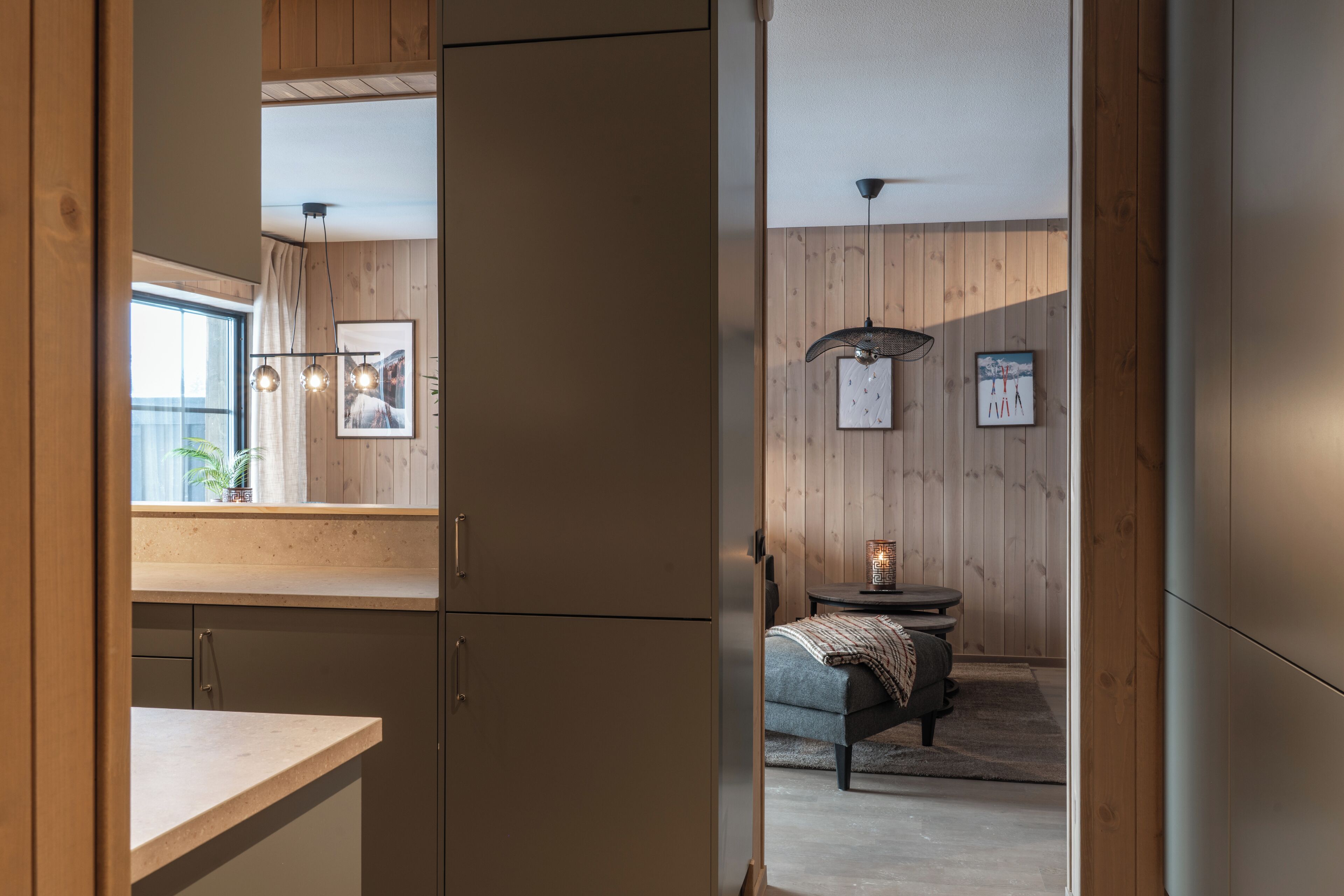 A modern interior with wooden panel walls, a kitchen area with a countertop, and a seating area with a table and chairs.