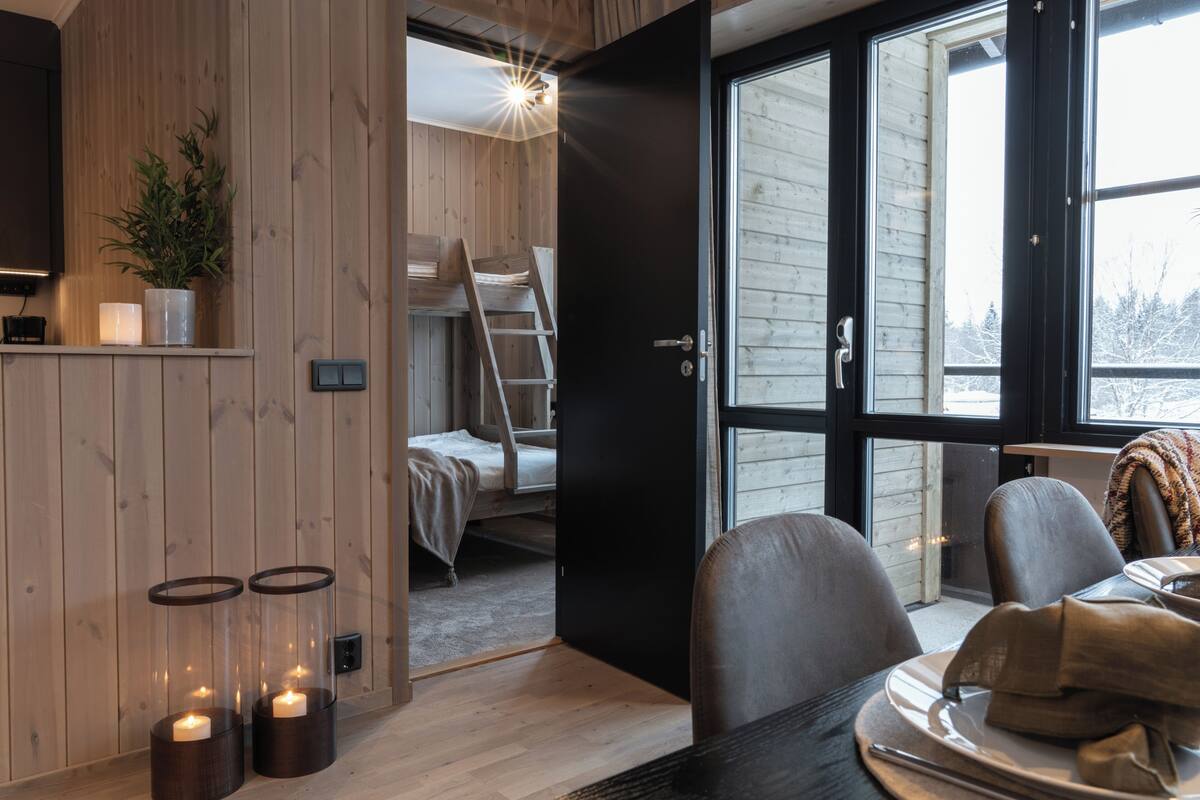 Ein Zimmer mit einem Bett, einer Leiter, einem Tisch mit Tellern und einer Tür zu einem weiteren Raum.