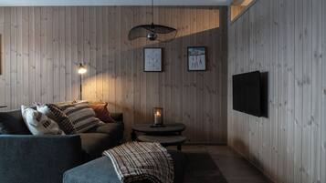 Une pièce confortable avec un canapé, une petite table avec une lampe et un téléviseur fixé au mur.