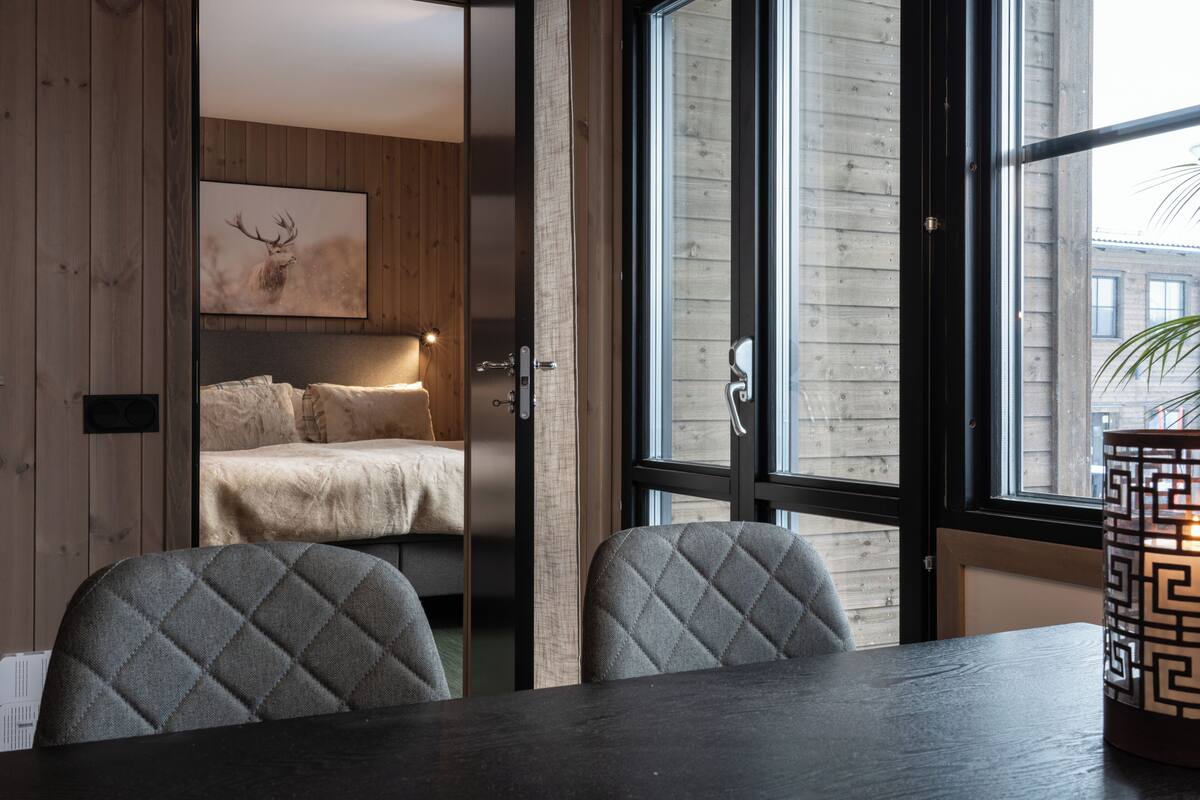 Ein modernes Zimmer mit einem Bett, einem Esstisch und einem Fenster mit Blick.