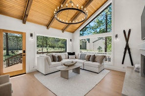 A modern living room with a sectional sofa, a coffee table, and a large window offering a view of the outdoors. - Luxurious Sunriver Home with Access to Exclusive Golf (Sunriver)