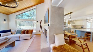 Ein modernes Wohnzimmer mit einer Couch, einem Kamin und einem Essbereich mit Tisch und Stühlen.